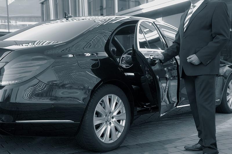 Chauffeur of an executive car service opening the door of a limousine.