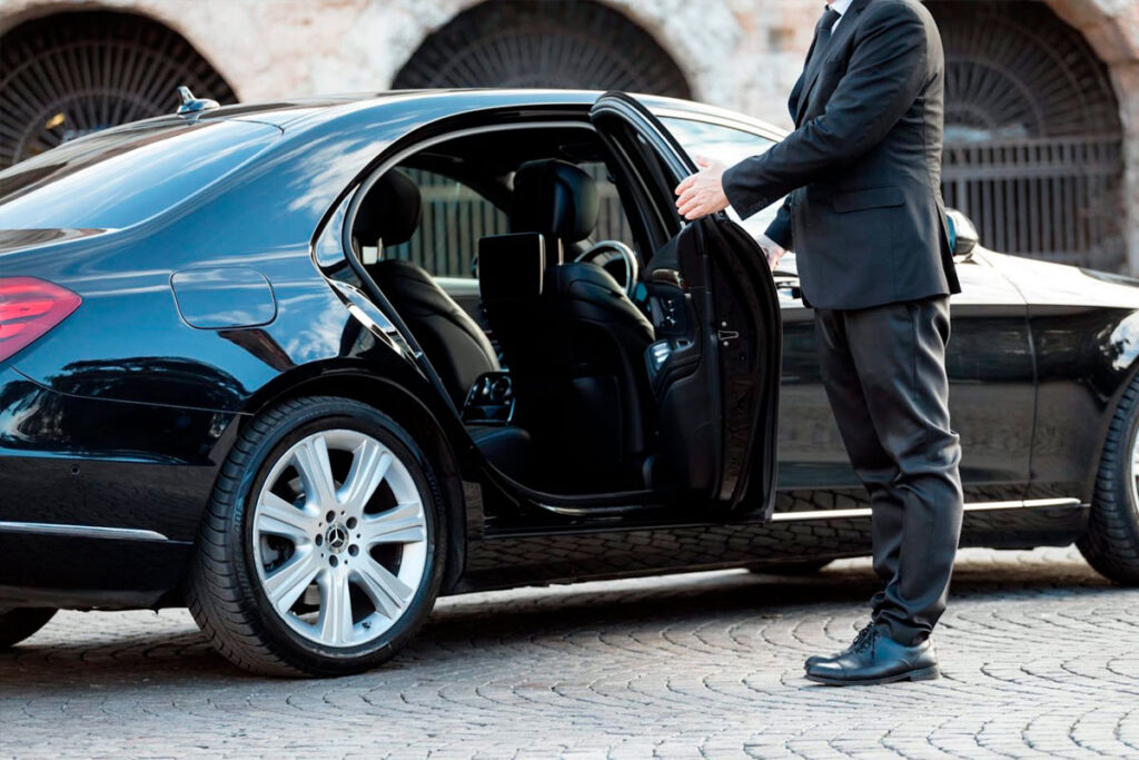 A chauffeur opening the door of a limousine.