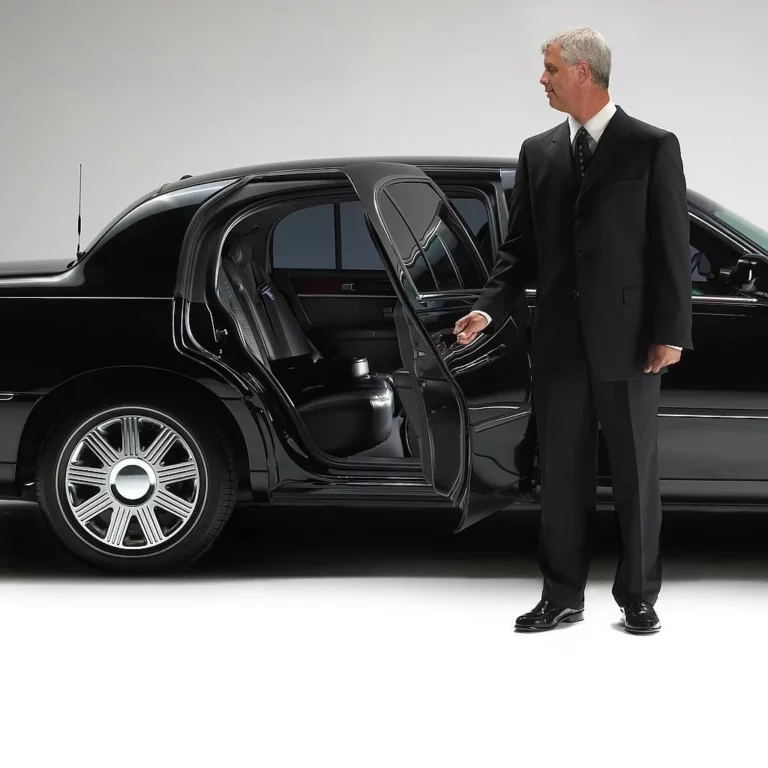 Driver of a chauffeur service is opening the door of a limousine.