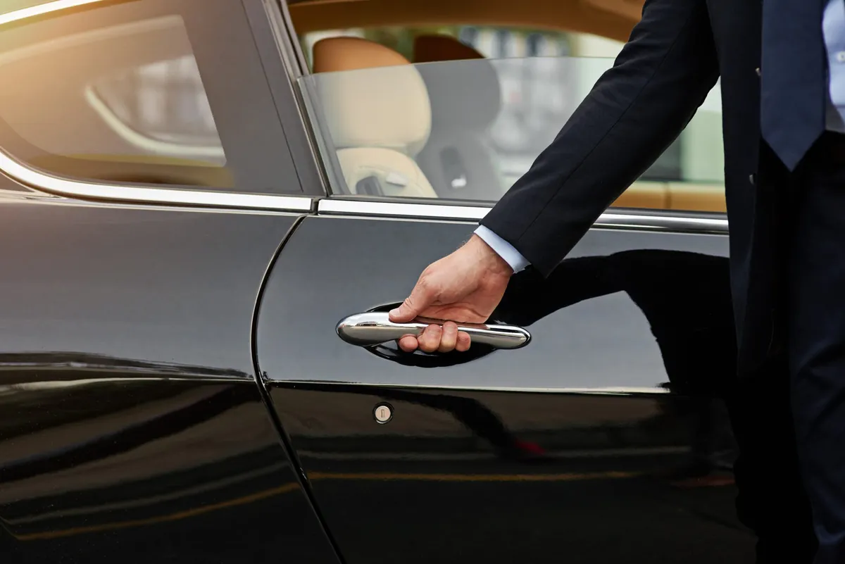 Chauffeur opening the door of a black car for a wine tour pickup