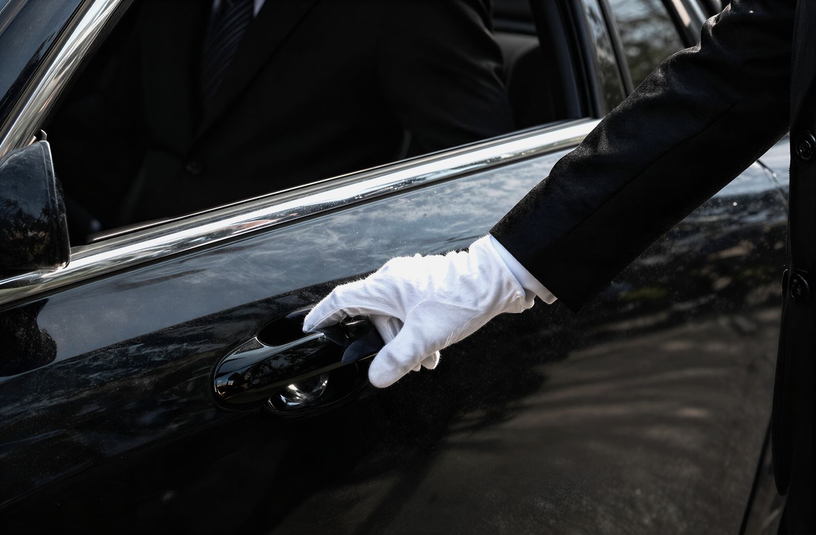 Chauffeur opening the rear door of a black luxury car