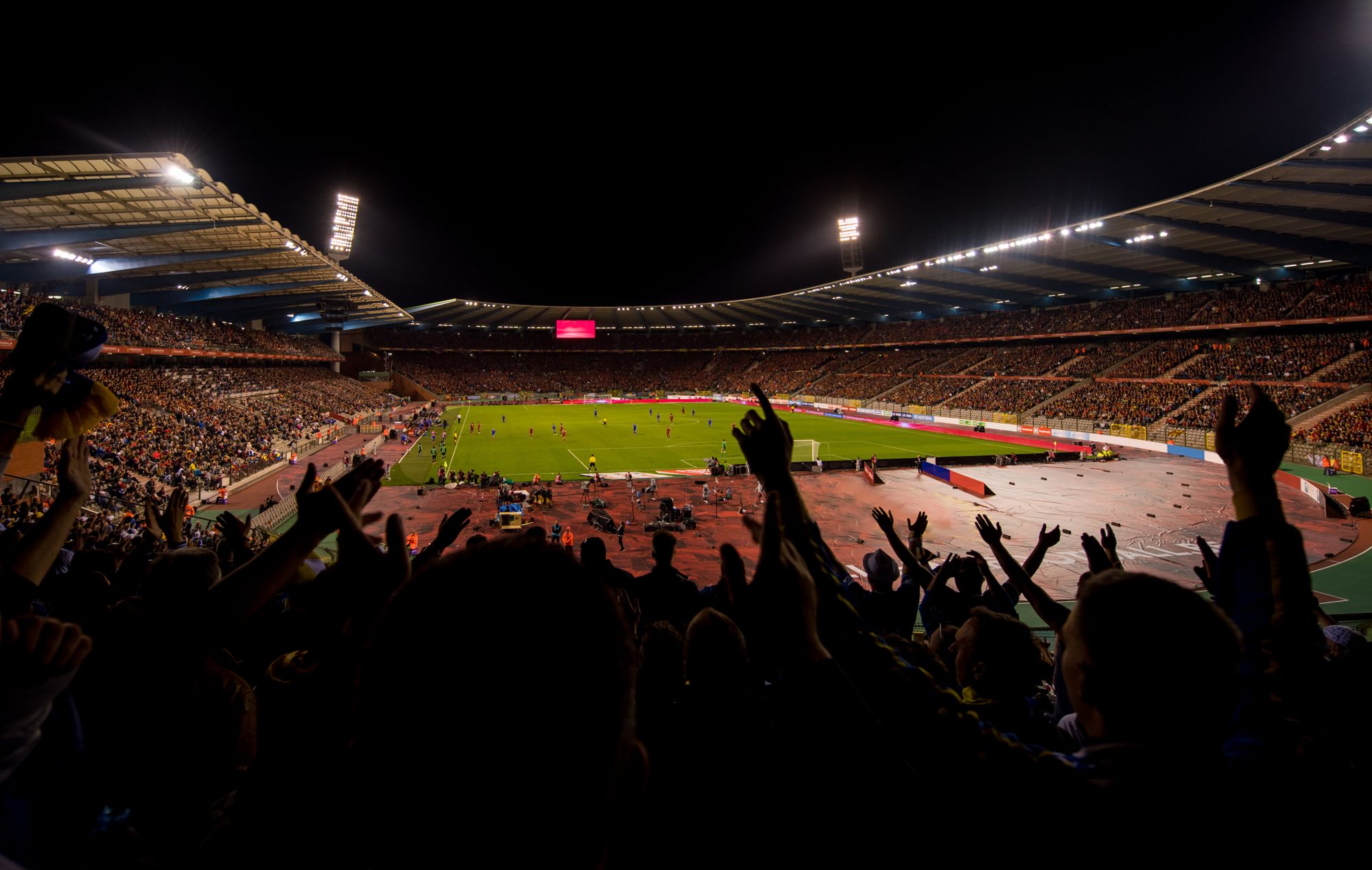 Crowd of fans in the stands of a packed stadium at night